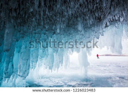 Ice cave on Lake Baikal in winter. Small silhouette of man