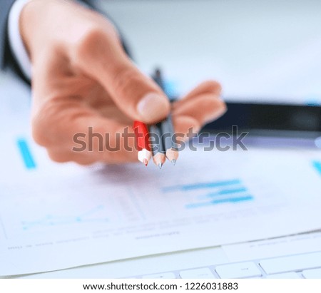 Man's hand giving color pencils that you can make notes in charts and tables.