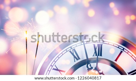 countdown clock and two sparklers in festive atmosphere, abstract bright night sky as light background, beautiful celebration concept for New Year's Eve party Royalty-Free Stock Photo #1226040817