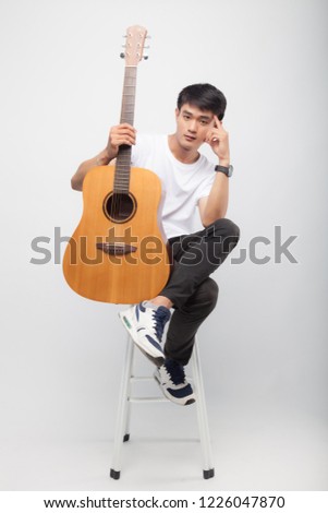 handsome asian man play guitar on grey / white background