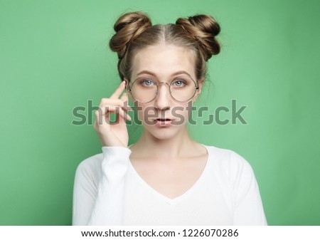 Studio shot of good looking female, doesn`t have much experience, wears big round spectacle.Caucasian college student recieves good proposal. Lifestyle and people concept.
