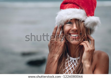 Christmas portrait smiling young woman in red santa hat close-up.Christmas beach vacation travel woman wearing Santa hat enjoying christmas on tropical beach. 
