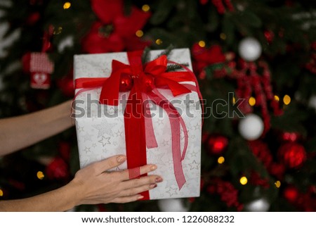 girl holding a New Year's gift on the background of the Christmas tree