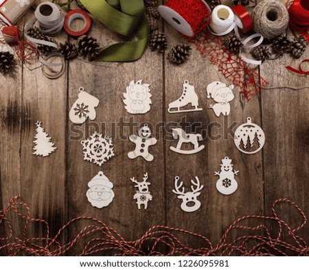 A set of various wooden Christmas toys ( mitten, Christmas tree, snowflake, pig, deer, snowman, horse, Santa Claus, gingerbread man and others) lies on a wooden table surrounded by ribbons and cords