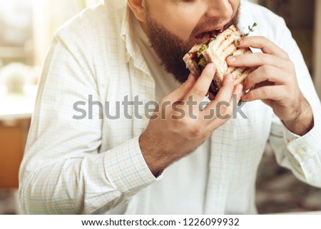Portrait of man eating in cafe and enjoying food. A happy bearded man rejoices in a restaurant, consuming his food, which he ordered. The concept of restaurant business and service.
