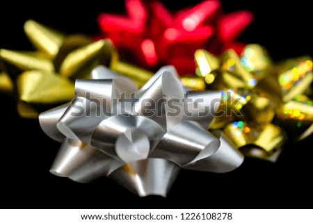 Red, gold, and white bows in an arrangement on black background: close up side view 
