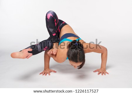 Young attractive woman practicing yoga doing Ekapada Yogadandasana Pose in full length, isolated over white studio background