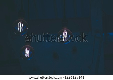 Creative idea of ​​lighting a bulb above the ceiling against the background of blue neon
