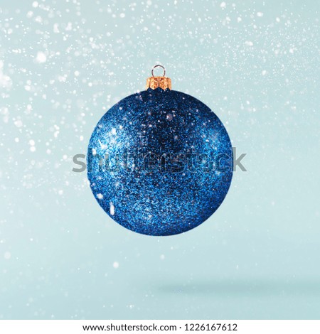 Christmas concept.  Creative Christmas conception made by falling in air shiny bauble over blue background. Minimal concept