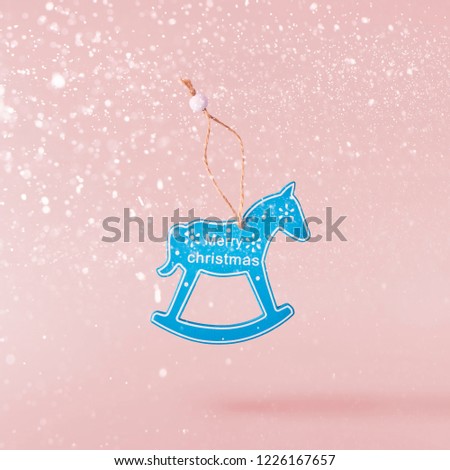 Christmas concept.  Creative Christmas conception made by falling in air christmas wooden tiny horse over pink background. Minimal concept