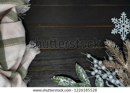 Cozy winter Christmas holiday background with pink green plaid blanket and silver and gold floral leaves elements. Flat lay style on wood background