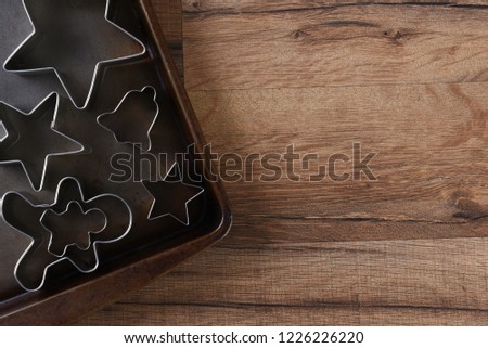 Closeup overhead view of a group of assorted cookie cutters on a baking sheet. Stars, gingerbread men and bell are shown.