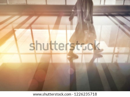 Blur image part of female doctor is walking with flare light and light reflection on surface of hallway in hospital on morning time, lifestyle with interior design concept 