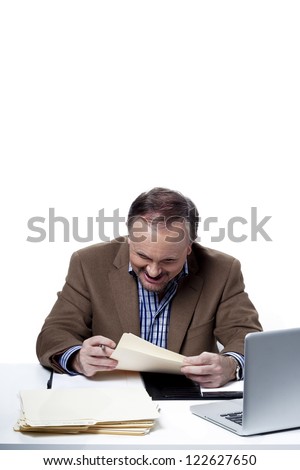 Mature businessman reading a report at work, , Model: Dan Sanderson