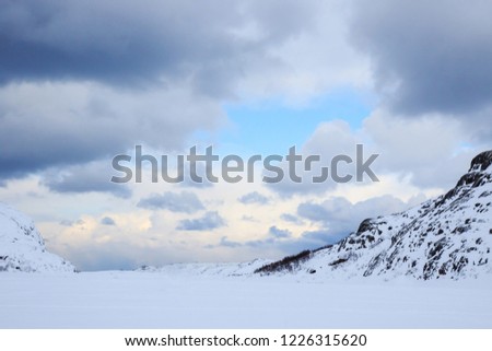 Snow and sun, winter snowy mountains  landscape. Winter time, Russia, beautiful arctic wild nature of northern hills. Beautiful snow winter ice and cold scenery view, blue sky with grey season clouds