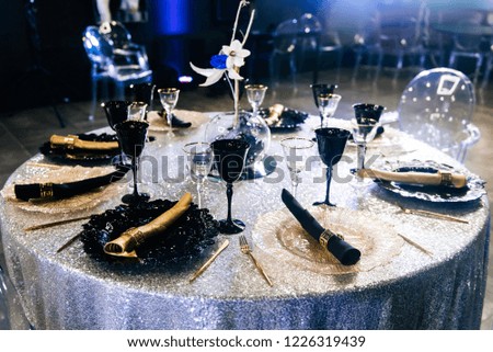 Tables set for an event party or wedding reception. luxury elegant table setting dinner in a restaurant. Black and gold glasses and dishes.