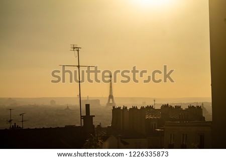 Eiffel Tower seen from the Montmartre neighborhood with simple houses and rooftops on the amazing landscape of Paris, France. A scene showing the Parisian life in Europe.