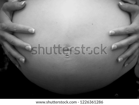 Lovely woman hands on her pregnant 
belly , black and white picture