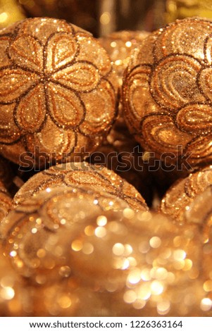 Golden Christmas baubles or balls handmade of glass. Gold flower ornaments with glitter sparkling for the winter season, Christmas tree decoration. Elegant and festive design glowing with the lights 