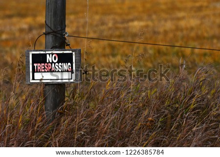 An image of an old no trespassing sign on a fence post. 