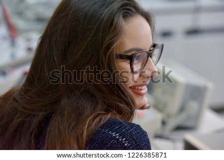Young female student wearing glasses with long brown hair sitting with smile listening teacher in technical vocational training, the lesson in technical college.