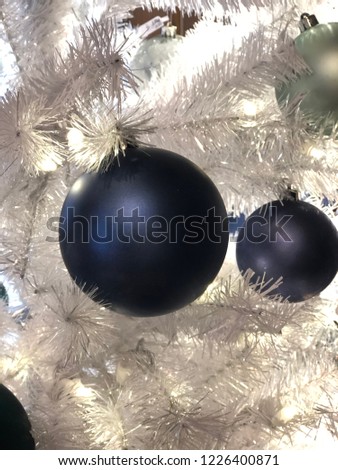 Close up of beautiful blue ornaments hanging on a white Christmas tree