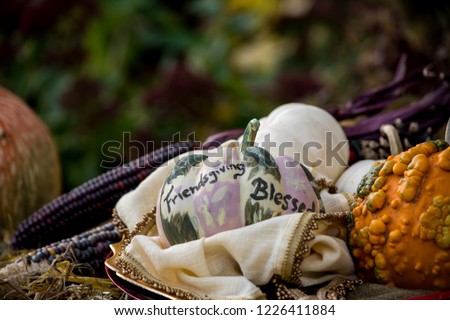 Friendsgiving on Thanksgiving day rustic centerpiece with decorative pumpkins and traditional Thanksgiving day items on hay bale with indian corn autumn harvest concept words Friendsgiving blessed