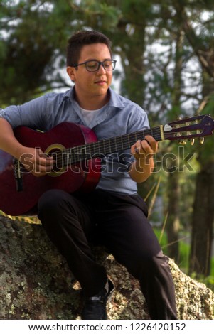 Young man playing guitar in the forest