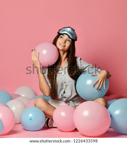 Portrait of trendy cheerful young woman having many color air balloons looking up enjoying ballons isolated on pink background. Celebration and party. Having fun