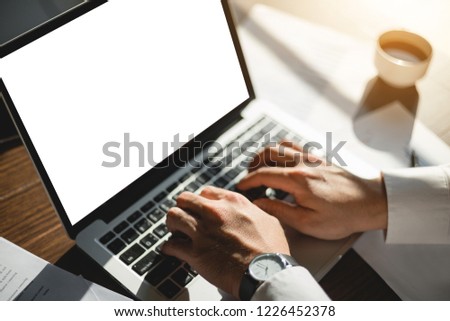 mockup computer,laptop,business man searching information in workplace with laptop computer,cell phone,various items on desk in office.design creative work space on wooden desktop with various items