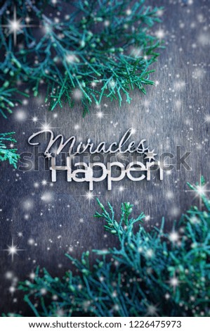 Inscription miracles happen and fir branches on a wooden background. Concept of inspiration and hope. Top view. Snow effect.