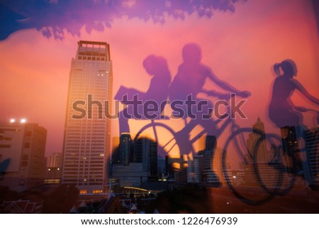 Mirror image, internal view of a book shop and mirrored picture of children ride bike in foregrounds. Bangkok City at twilight backgrounds. Beautiful light and sky. Thailand. City art concept.
