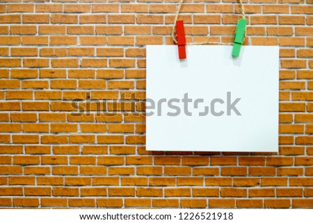 White paper note with word happy and emotion sticking out tongue hanging on orange brick background. Colorful wood clips. Free space for any text design. Can be use for advertising, banner.
