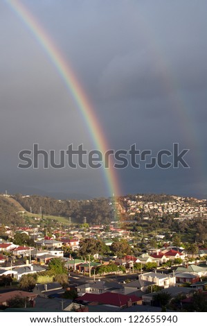 Double rainbow over urban landscape with dark clouds as a backdrop