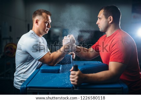 Arm wrestlers fighting, dust from talc in the air