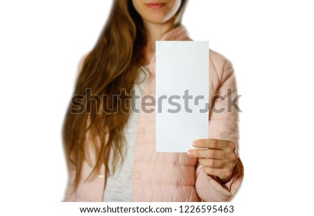 A woman in a warm winter jacket holding a white leaflet. Blank paper. Close up. Isolated on white background.