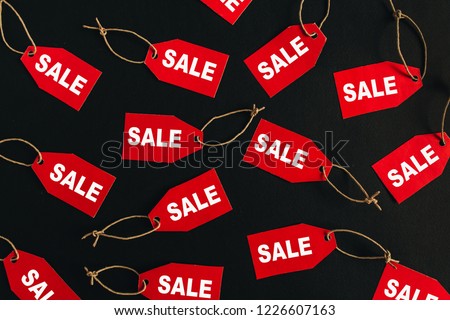 Black Friday sales discount composition. Red tags with word SALE on black background. Flat lay, top view.