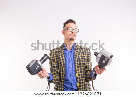 Technologies, photographing and people concept - portrait of funny young brunette man taking selfie with two cameras on white background