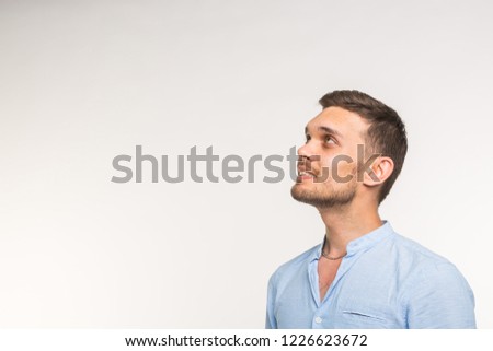 Expressions and people concept - Handsome cheerful young man looking up over white background with copy space
