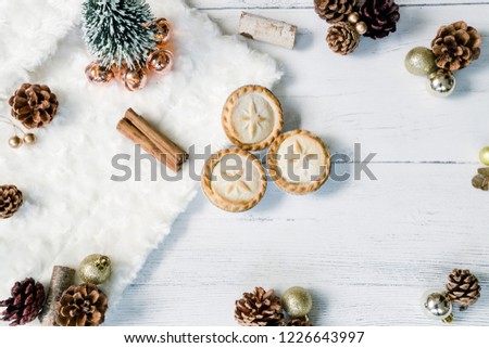 Mince pies and cinnamon sticks. Christmas tree with golden baubles and pine cones on a white background. Christmas themed flat lay image for a blog.