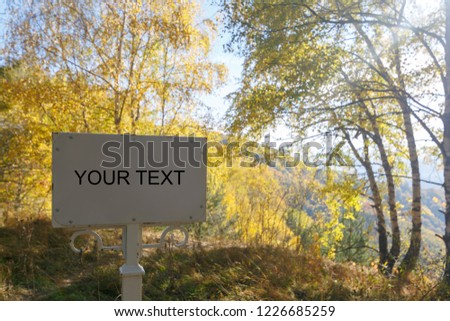 Metal plate with your text against the backdrop of a beautiful autumn landscape on a sunny day