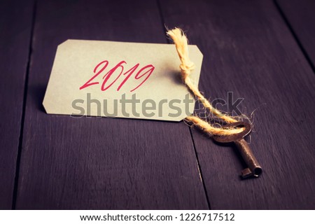 Christmas background. Old key with a tag and the inscription 2019. Dark wooden background. Christmas background.