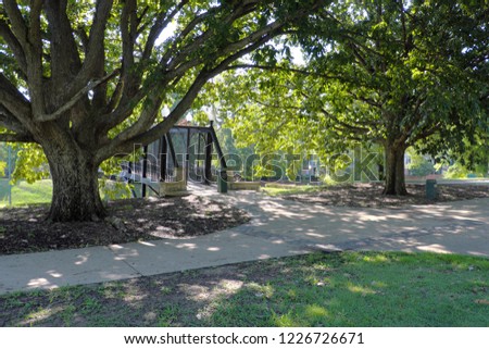 Public park near the black metal bridge across the road and green trees and lawn scenery, Memphis, Tennessee.