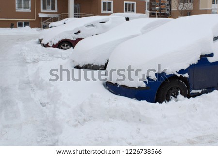 Cars under snow cover in winter parking