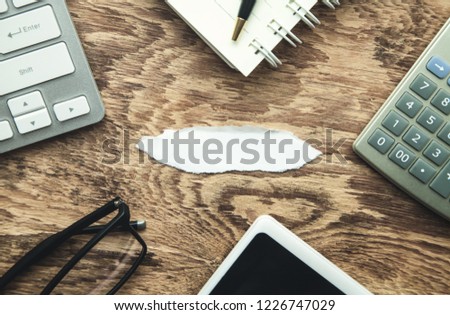 Piece of torn paper with business objects on wooden table. Business concept
