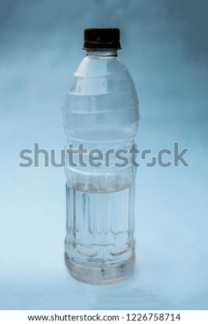 Plastic water bottle isolated on white or bluish background with having some water in it.Close up view.