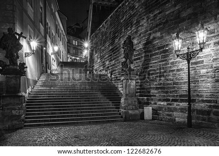 dark stairs with two statues enlightened historical lanterns in black & white design