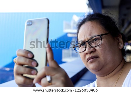 Asian girl holding smartphone for self-portrait photo with view of skyscrapers during summer travel vacation.