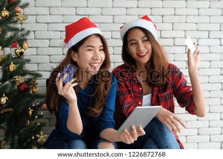 Two young cute asia women holding smartphone  and credit card for shopping online background,mock up, with happiness, Christmas holiday shopping concept