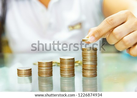 Saving money, woman stacking coins into increasing columns. Royalty-Free Stock Photo #1226874934